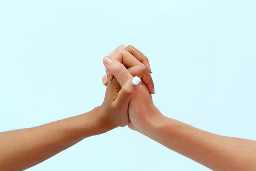 White caucasian female hands and black african american hands hold fingers together in world unity and racial love and understanding in tolerance and racial diversity cooperation concept on blue background