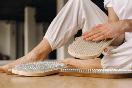 A man holds in his hands boards with nails for yoga classes.