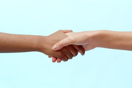 Caucasian and black African American woman shaking hands on a blue background. Racism concept and all lives matter.