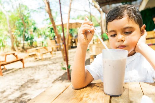 Latin boy drinking cocoa with milk in a restaurant in the countryside of Managua Nicaragua
