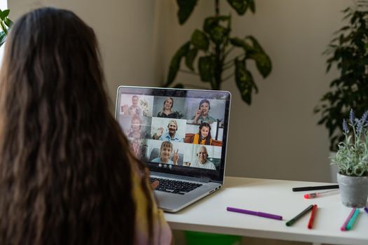 Home schooling. A girl is sitting at a table with a laptop during an online video chat of a school lesson with a teacher and class. Concept of distance education. Self-isolation in quarantine