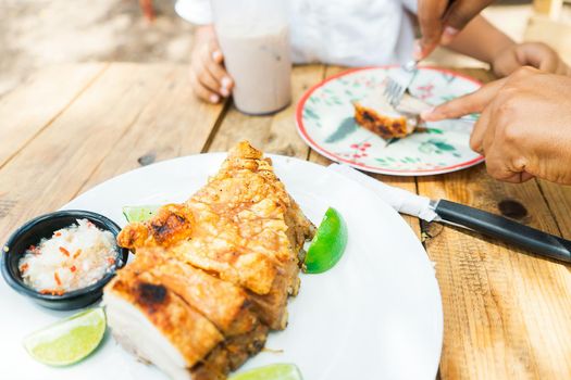 Closeup at the table of a family from Nicaragua eating pork belly