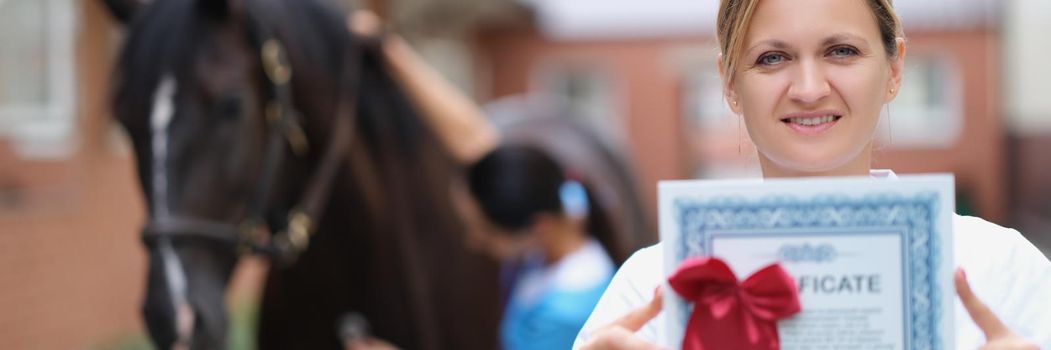 Woman doctor shows horse veterinary certificate, close-up, blurry. Equestrian sports tourism, competitions