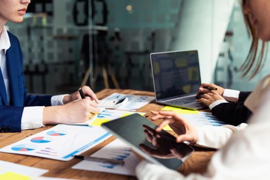 Male businessman holding pen to take notes summarizing marketing strategy with female colleagues in meeting, teamwork, investment planning.