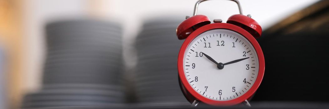 Red alarm clock on the kitchen table, close-up, blurry. Time for preparing a banquet, order fulfillment time in a restaurant