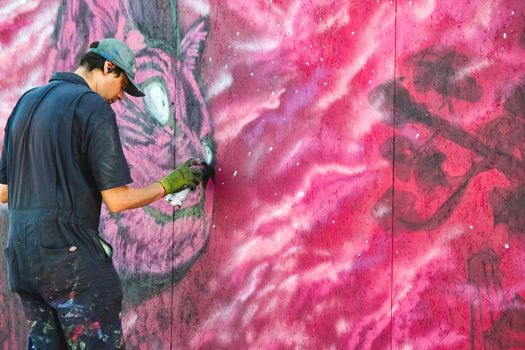 TaQali, Malta - June 04 2022: A street artist painting a pink wall mural of a cat