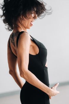 A woman in black sportswear is engaged in dynamic kali meditation in the Yoga hall.