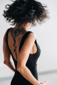 A woman in black sportswear is engaged in dynamic kali meditation in the Yoga hall.