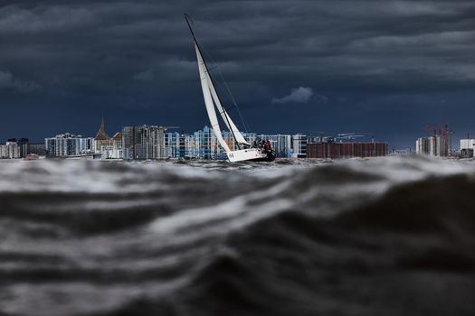 Russia, St. Petersburg, 17 June 2022: The residential complex under construction on the embankment of the Neva River on Vasilievsky island in stormy weather, construction cranes, sailing yachts. High quality photo