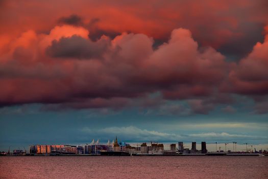 Magic pink sky over the residential complex under construction on the embankment of the Neva River on Vasilievsky island in sunset, bulk island, construction cranes. High quality photo