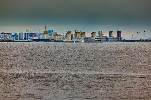 The residential complex under construction on the embankment of the Neva River on Vasilievsky island in sunset, bulk island, construction cranes. High quality photo