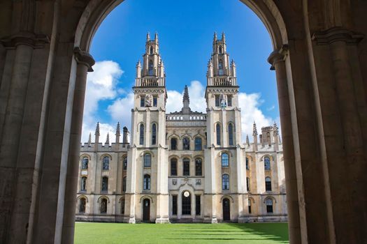 All Souls college, Oxford university - front view of entrance with towers and the green lawn from an archway