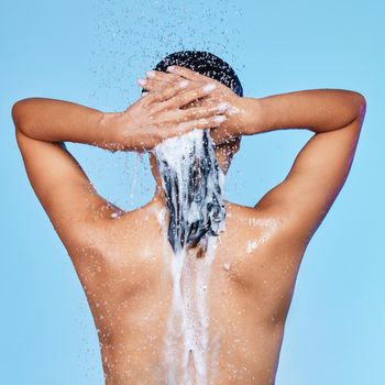 Rearview shot of an unrecognizable woman enjoying a soapy shower against a blue background.
