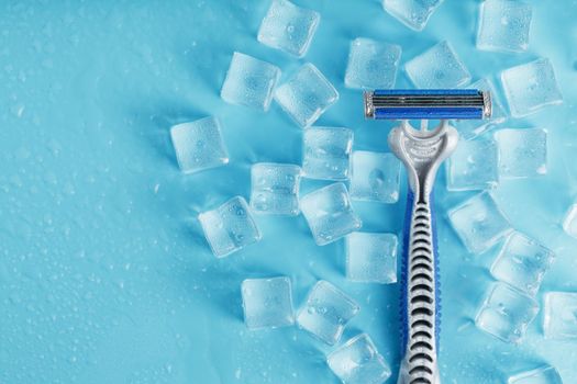 Shaving machine on a blue background with ice cubes. The concept of cleanliness and frosty freshness