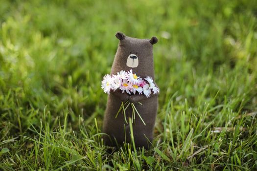 Eco-friendly cute handmade toy bear on grass at sunny summer day