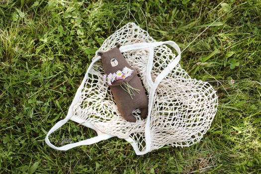 Eco-friendly cute handmade toy bear on grass at sunny summer day