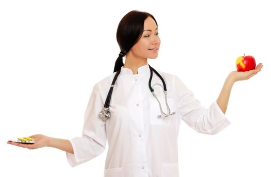 Female doctor holding apple and bunch of tablets isolated on white background