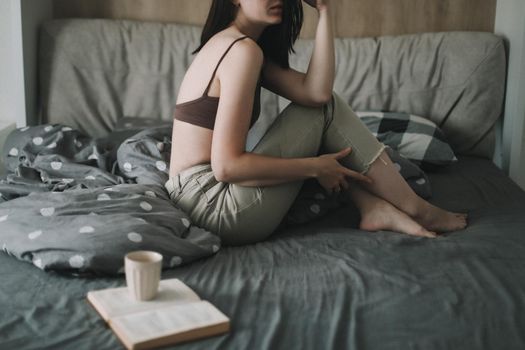 Young sexy woman portrait in bed with a book and coffee cup in the morning