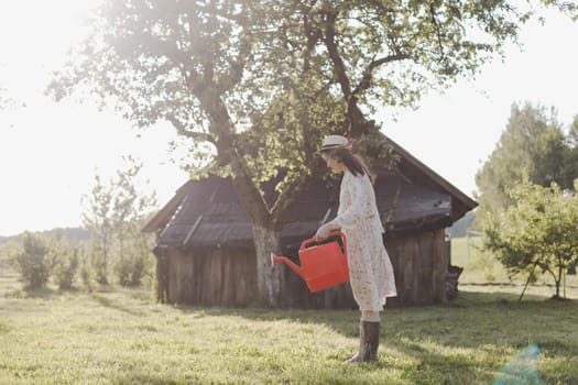 Young female gardener watering the plants in the garden in summer. Young woman with a watering can.