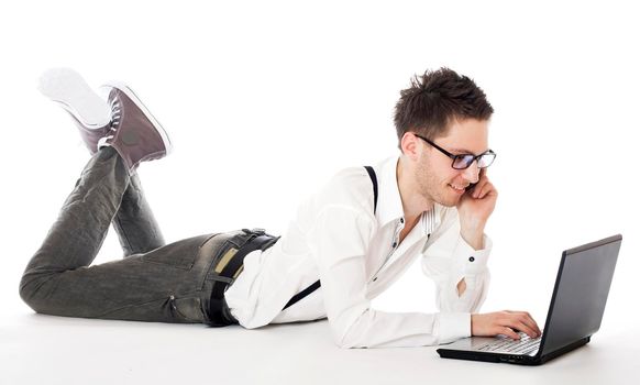 Businessman lying in front of laptop and calling on mobile phone. Isolated against a white background.