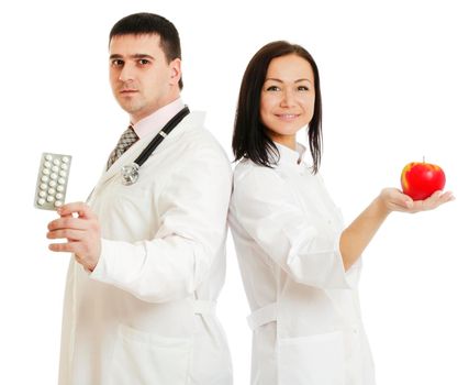 Male and female doctors holding apple and bunch of tablets isolated on white background