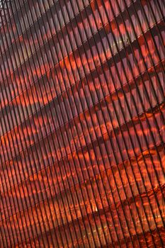 The glass and iron facade of huge skyscraper at sunset, steel, orange color, reflection of sun. High quality photo