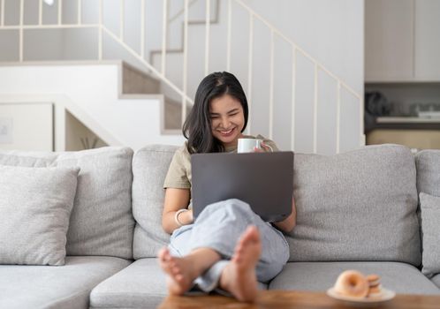 Happy young asian woman having conversation chatting while using laptop at house. Work at home, Video conference, Online meeting video call, Virtual meetings, Remote learning and E-learning.