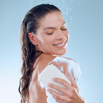 Studio shot of a young woman taking a shower against a blue background.