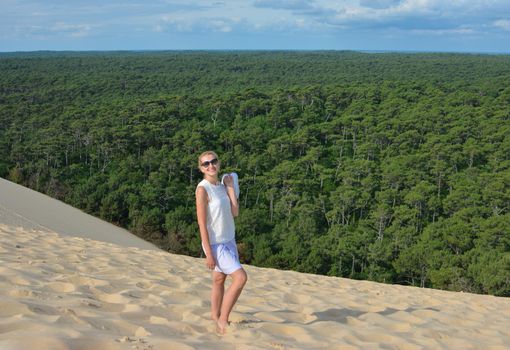 A girl in the background of a coniferous forest at Pyla dune, the largest sand dune in Europe, France