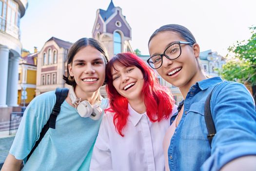 Having fun happy teenagers looking at camera, taking selfie. Three teenage friends together outdoor, on city street. Friendship, lifestyle, leisure, communication, youth concept