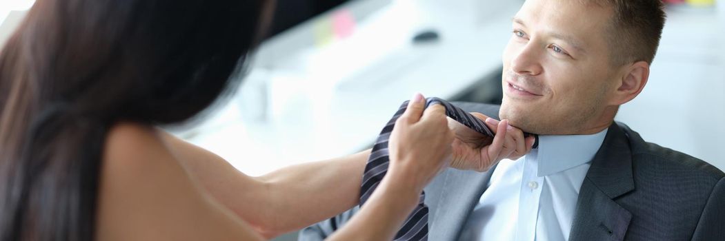Female supervisor pulls tie of young employee. Flirting workplace concept