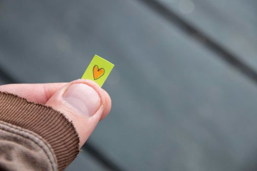 Hand holding a tag with a drawn heart. Love concept. High quality photo