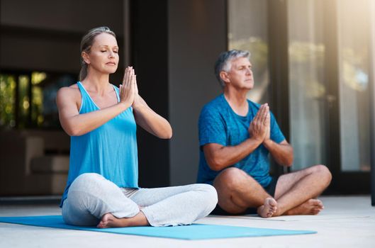 Shot of a mature and happy couple meditating outside of their home in the morning.