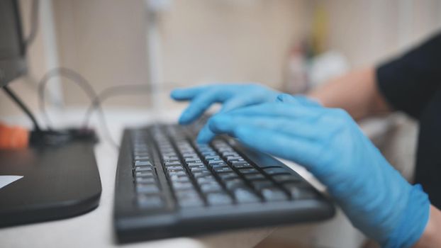 The veterinarian is typing on the keyboard in blue gloves