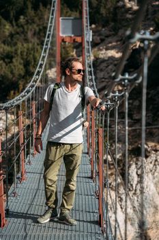 Portrait of middle-aged hiker passing by the hanging bridge and looking away. Travel concept.