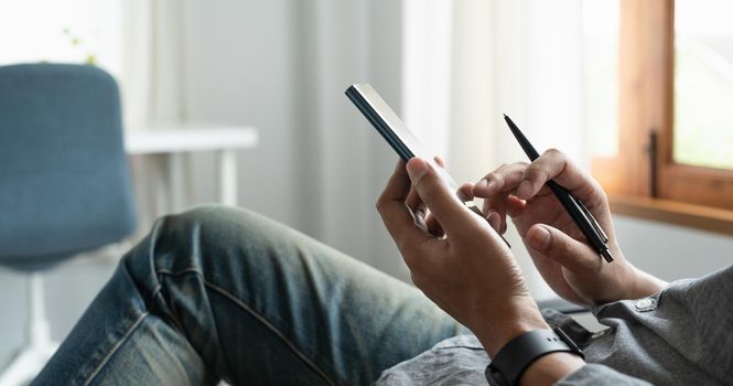 Cropped shot of businessman using mobile phone while sitting in modern office