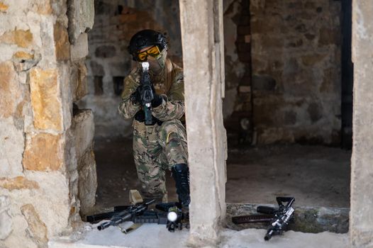 A woman in an army uniform shoots a firearm in an abandoned building