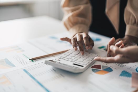 Close up Businessman and partner using calculator and laptop for calaulating finance, tax, accounting, statistics and analytic research concept.
