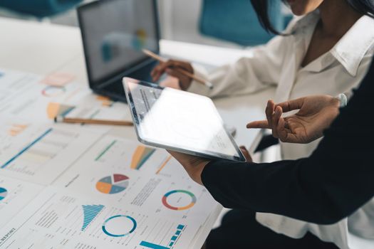 Business partnership coworkers using digital tablet to chart company financial statements report and profits work progress and planning in office room.