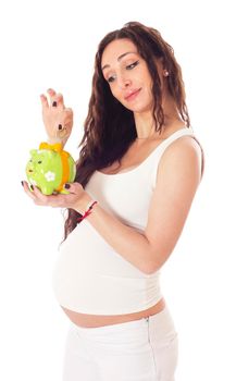 A woman putting money into a piggy bank in front of her pregnant belly. Isolated on white.