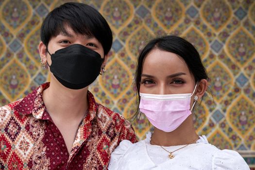 Portrait of a man with his transsexual couple wearing facial mask while looking at the camera