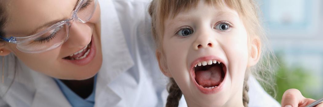 Portrait of cute kid visiting family doctor and open mouth pediatrician with tool check hurting throat. Healthcare, medicine, clinic, childhood concept