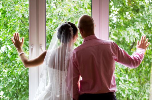 Bride and groom looking in the window at their wedding venue.