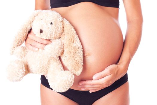 Pregnant woman holding soft toy, isolated on white.