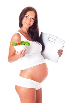 Pregnant woman holding scales in one hand to another salad, isolated on white.