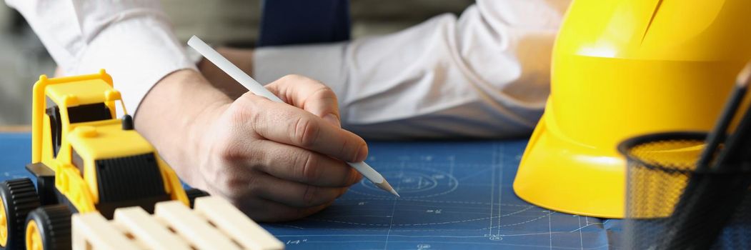 Close-up of male worker making corrections in construction planning with pencil. Qualified forewoman and blueprint on workplace. Renovation, build concept