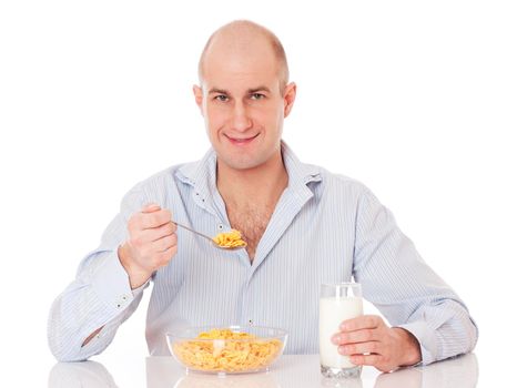 Young man eating very healthy breakfast consisting of corn flakes and milk. Isolated on white.