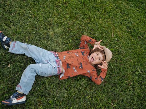 Small girl laying on a grass while grimacing