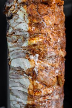 Close-up of vertical rotisserie marinated chicken meat for Doner Kebab, Turkish street food.