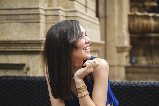 Elegant beautiful young woman looks towards the guests while sitting in a street cafe.